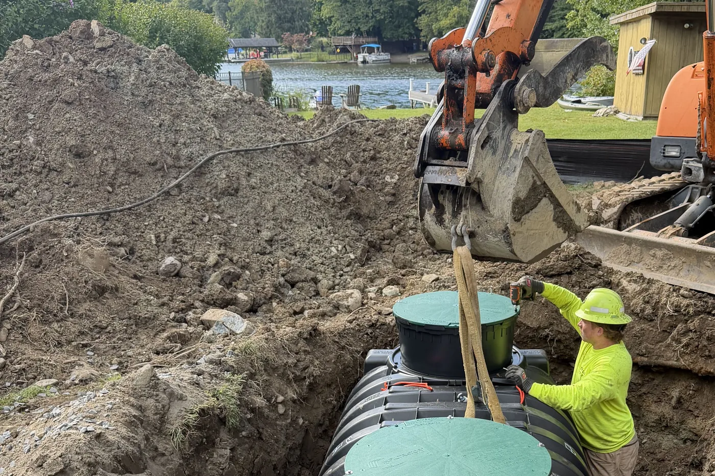 Aerobic septic system tank lowered into a rocky excavation by our excavator on a lakefront lot