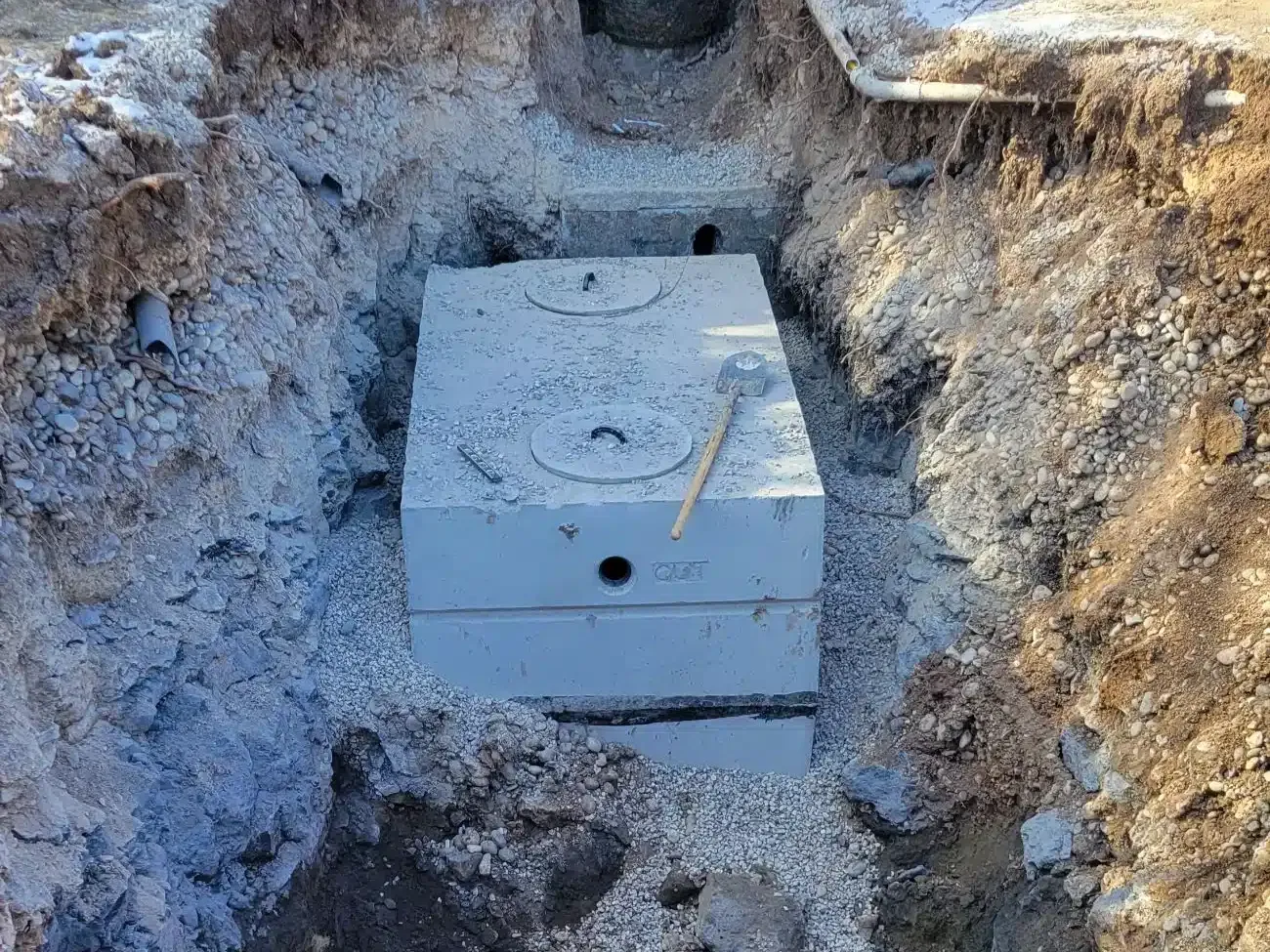 New concrete septic tank set on crushed stone in a rocky excavation