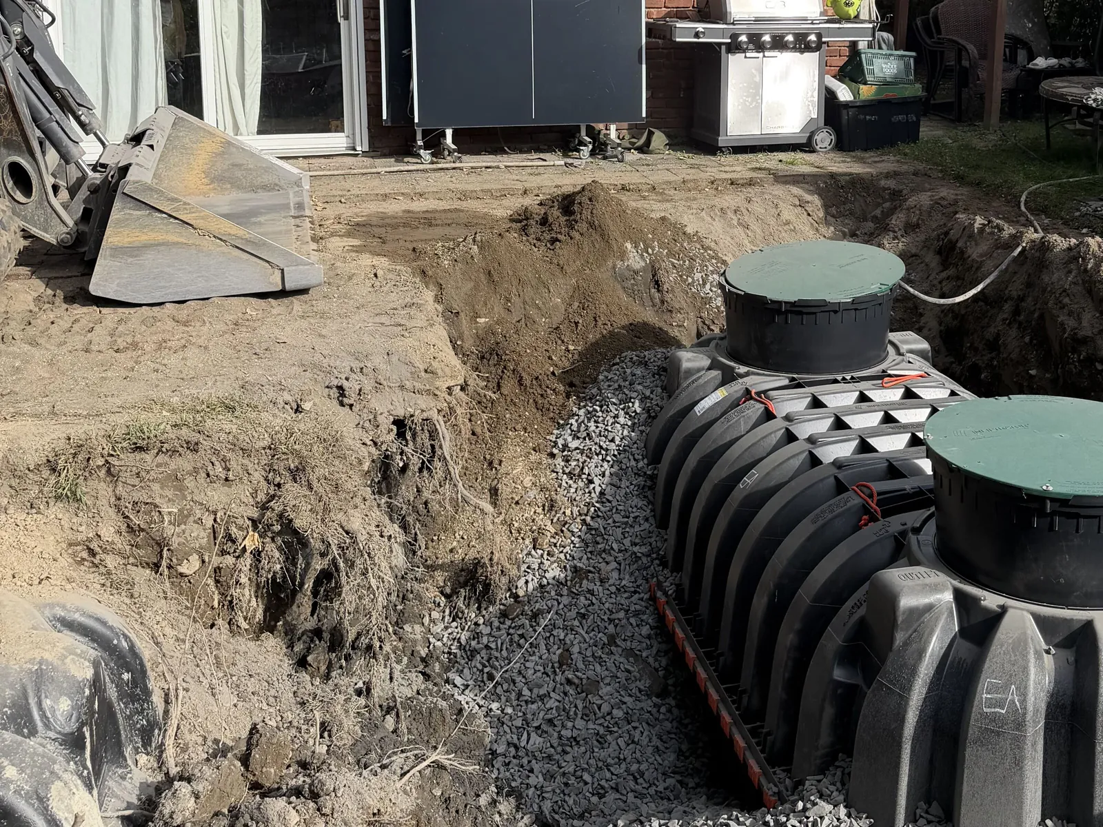 Septic treatment tank set on a crushed stone bed in an excavation behind a house