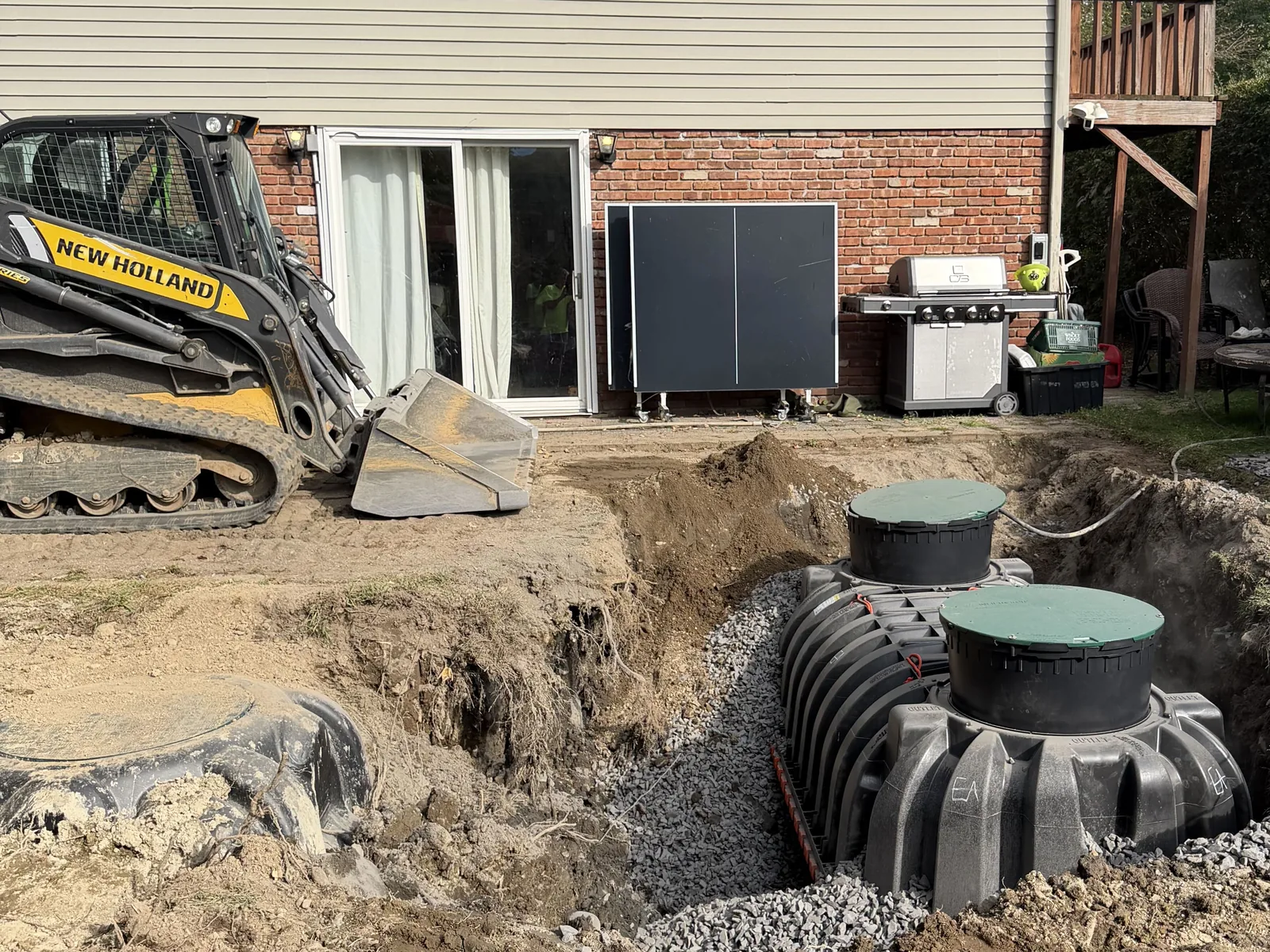 Our skid steer and the new treatment tank in the excavation behind a house