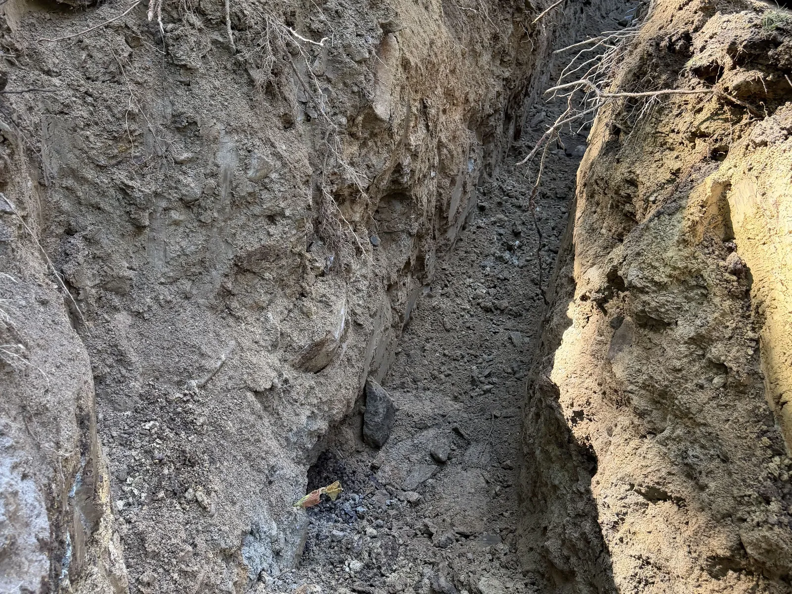 Trench cut through broken ledge and boulders on a wooded lot